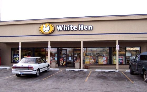 A white car is parked in front of a white hen restaurant