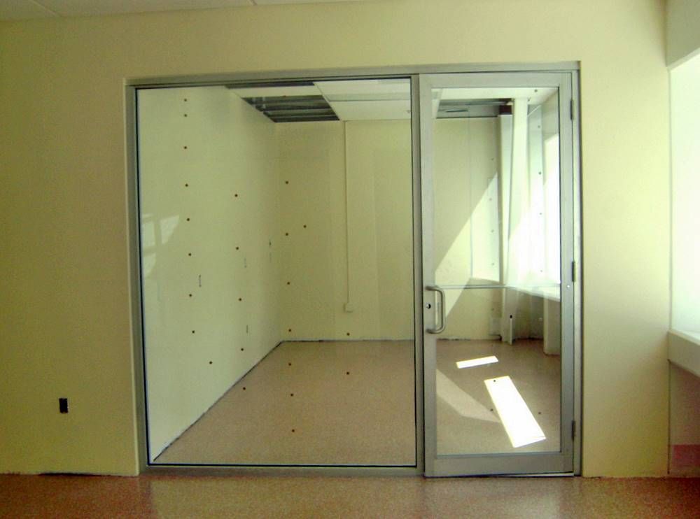 An empty room with a glass door between two walls.