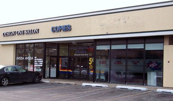 A car is parked in front of a store called copies