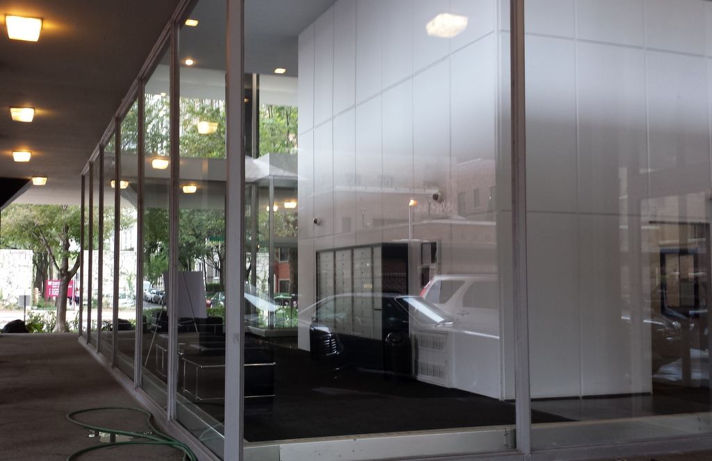 A building with a lot of windows and a reflection of cars