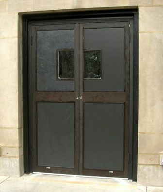 A pair of black doors with a window on the side of a building.