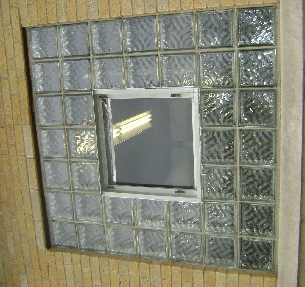 A window surrounded by glass blocks on a brick wall