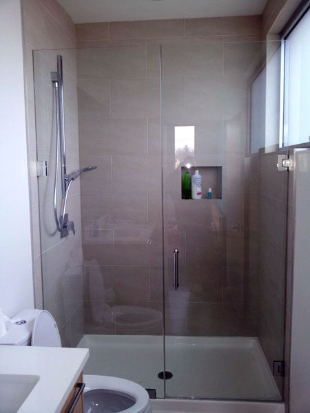 A bathroom with a glass shower door and a toilet