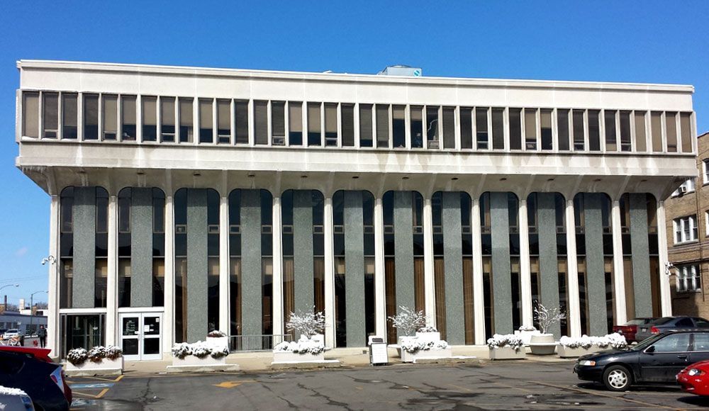 A large building with a lot of windows and cars parked in front of it.