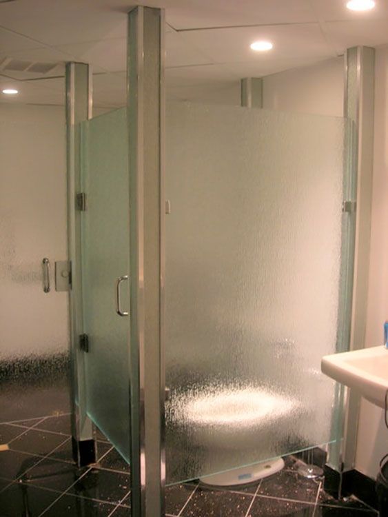 A bathroom with a toilet and a sink behind a glass partition.