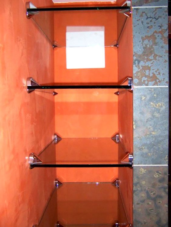 A row of glass shelves against an orange wall