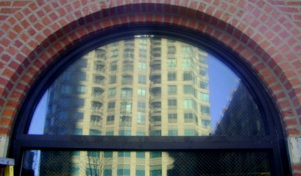 A large building is reflected in the window of a brick building