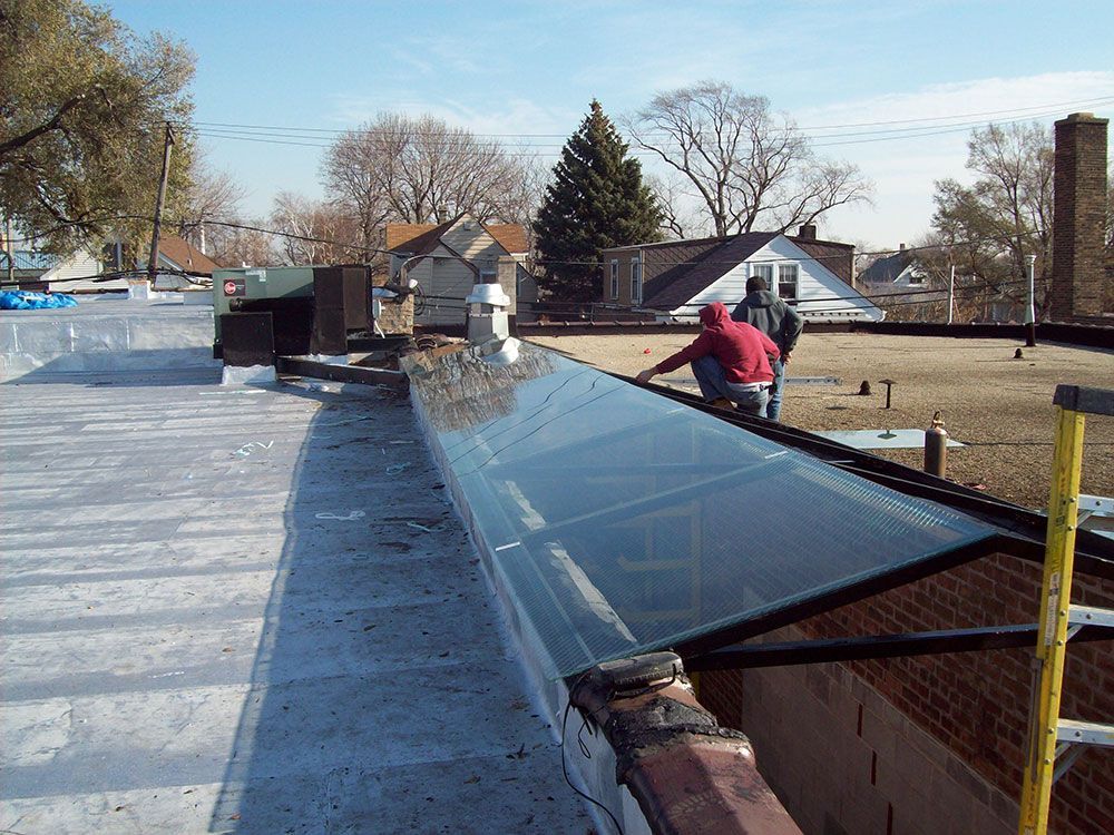 Two men are working on the roof of a building
