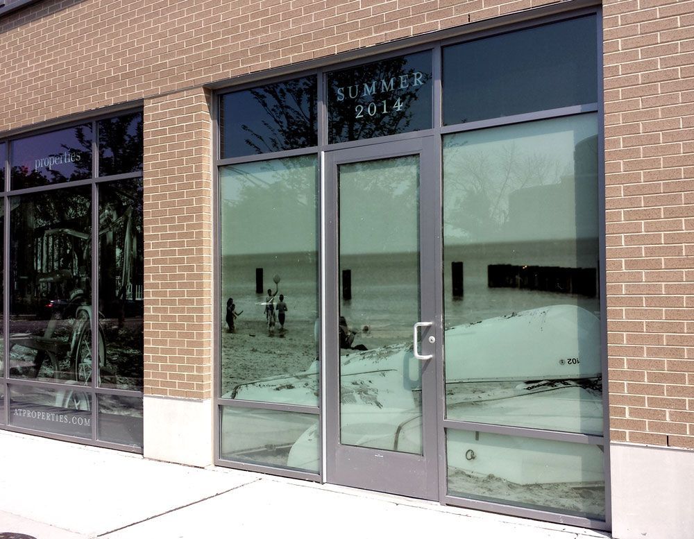 A brick building with a reflection of a beach in the windows.