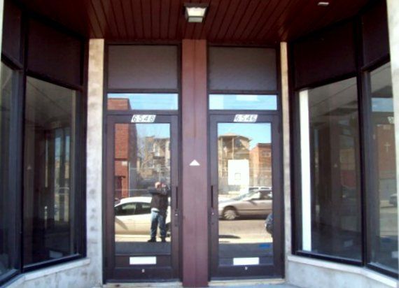 A building with a reflection of a car in the glass doors