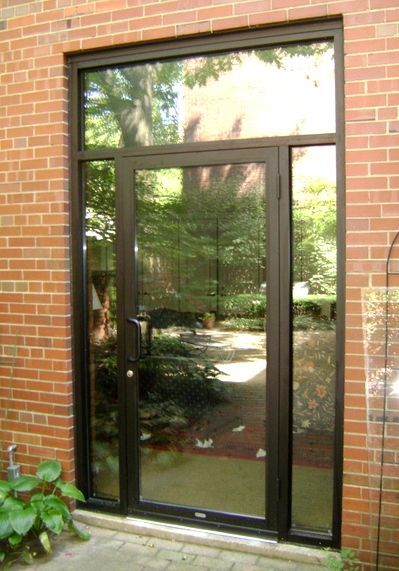 A large glass door with a brick wall behind it