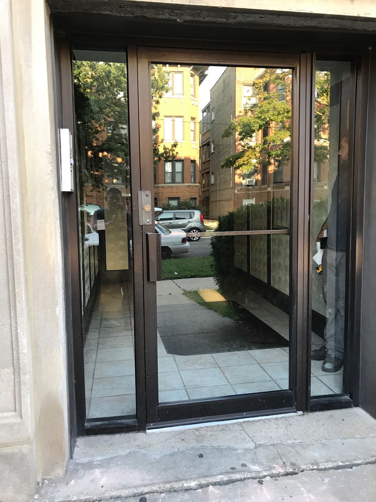 A man is standing in front of a building with a glass door.