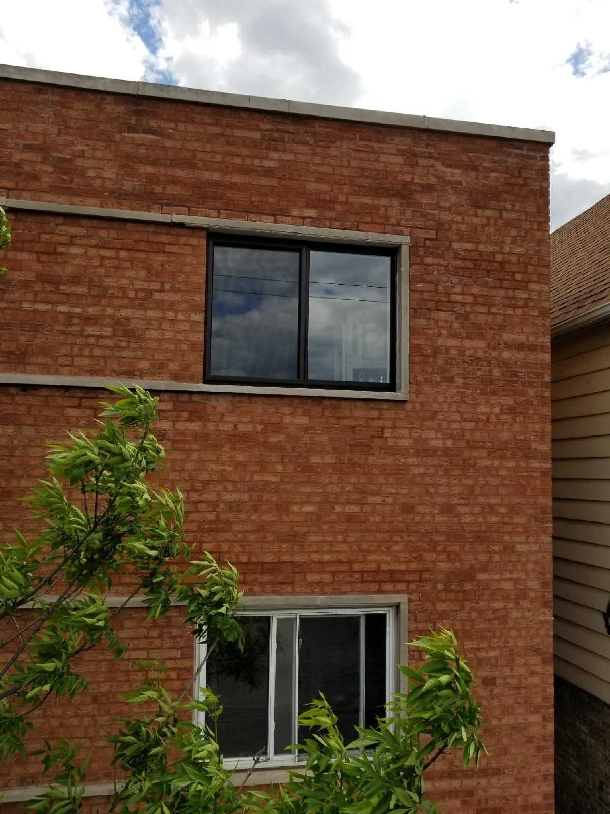 A brick building with a window and a tree in front of it
