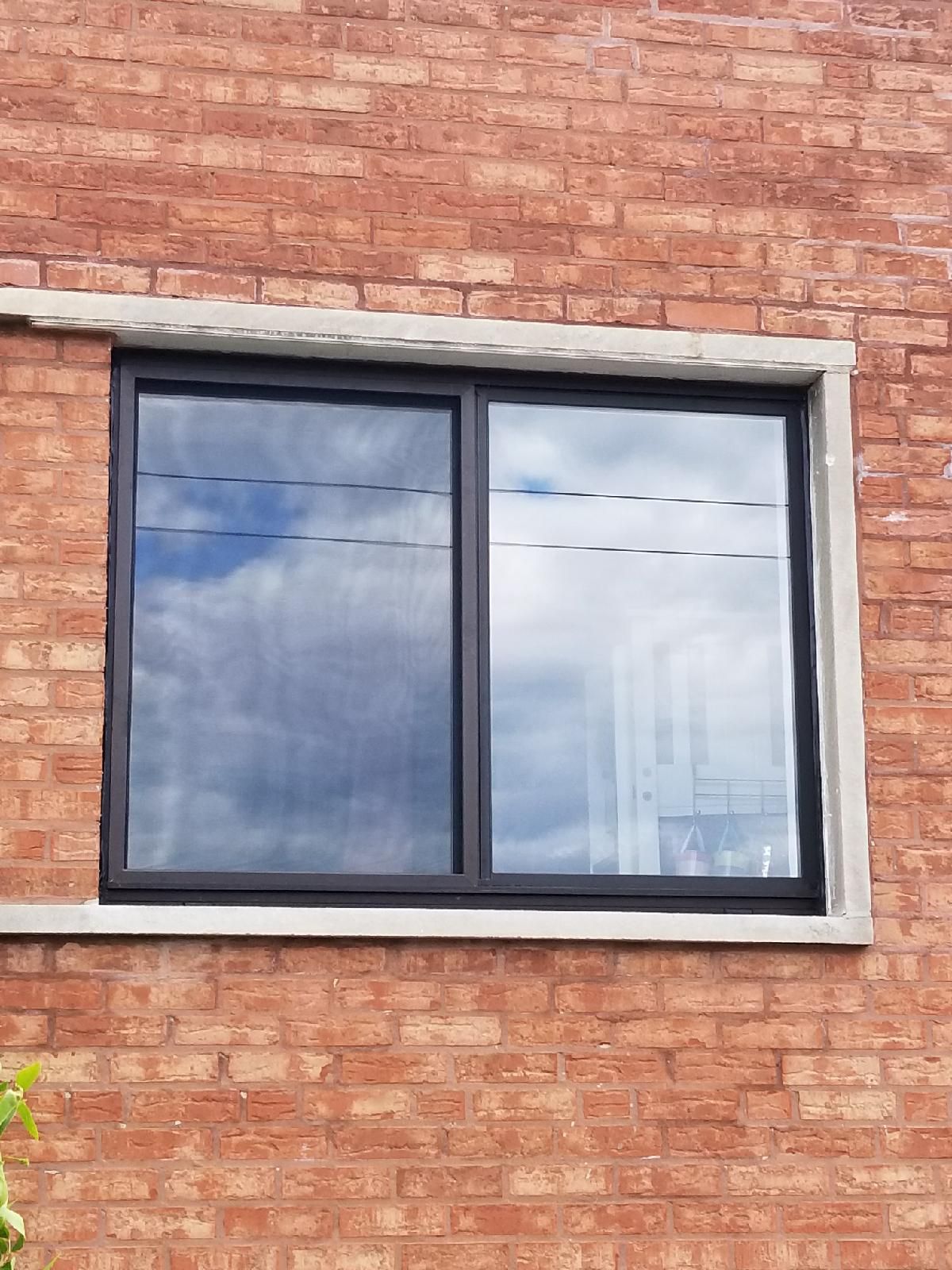 A window on the side of a brick building with a black frame.