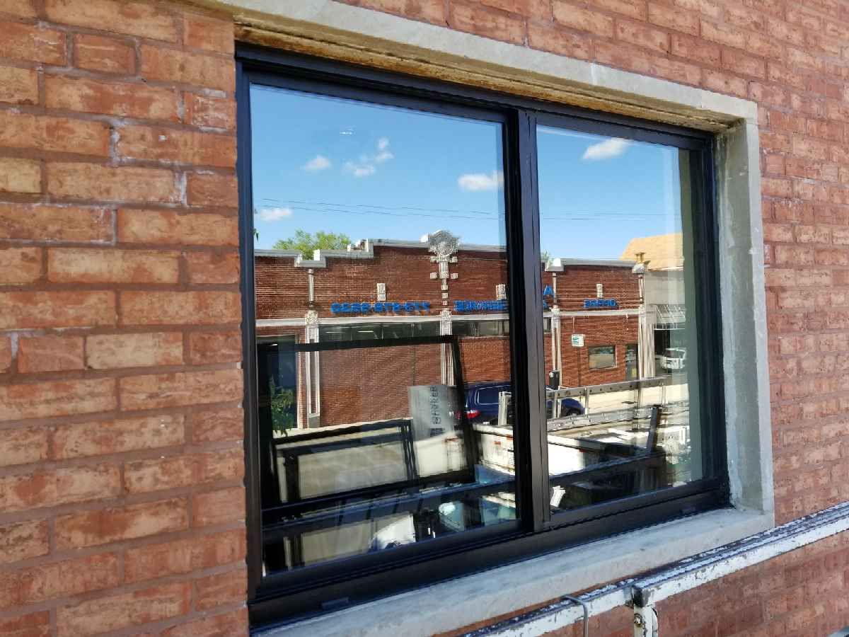 A window is being installed on a brick building.