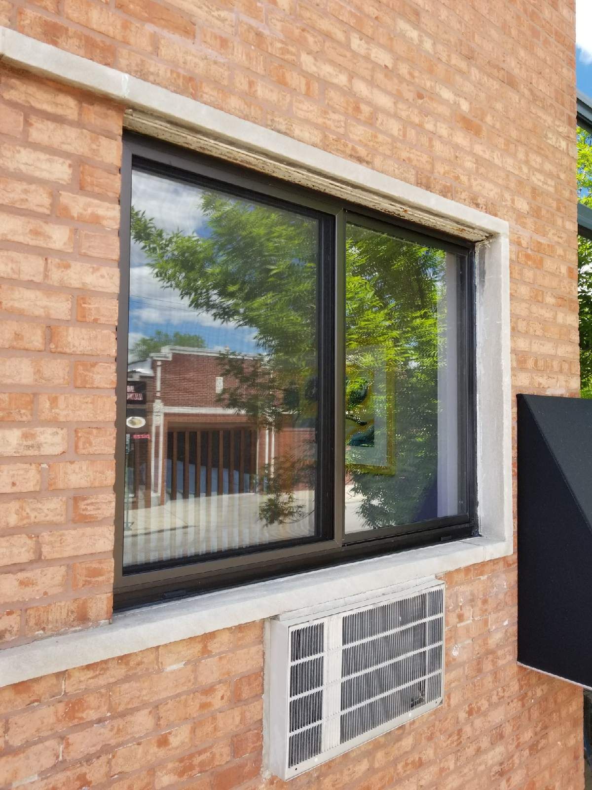 A brick building with a large window and air conditioner.