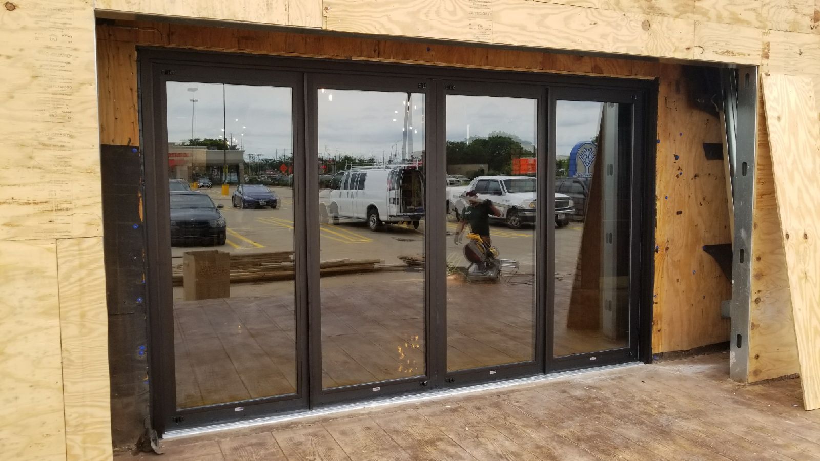 A large glass door is being built into a wooden wall.