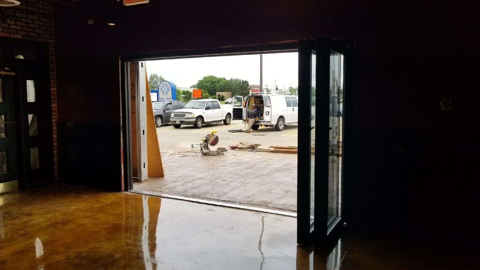 A garage door is open to a parking lot with cars parked in it.