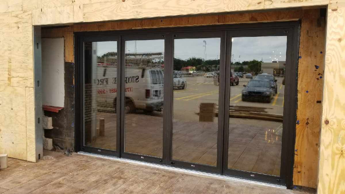 A large sliding glass door is being installed in a building under construction.