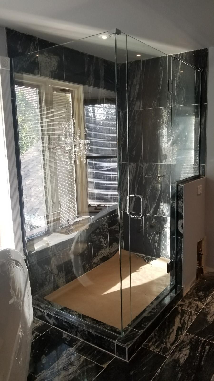 A bathroom with a walk in shower and a window.