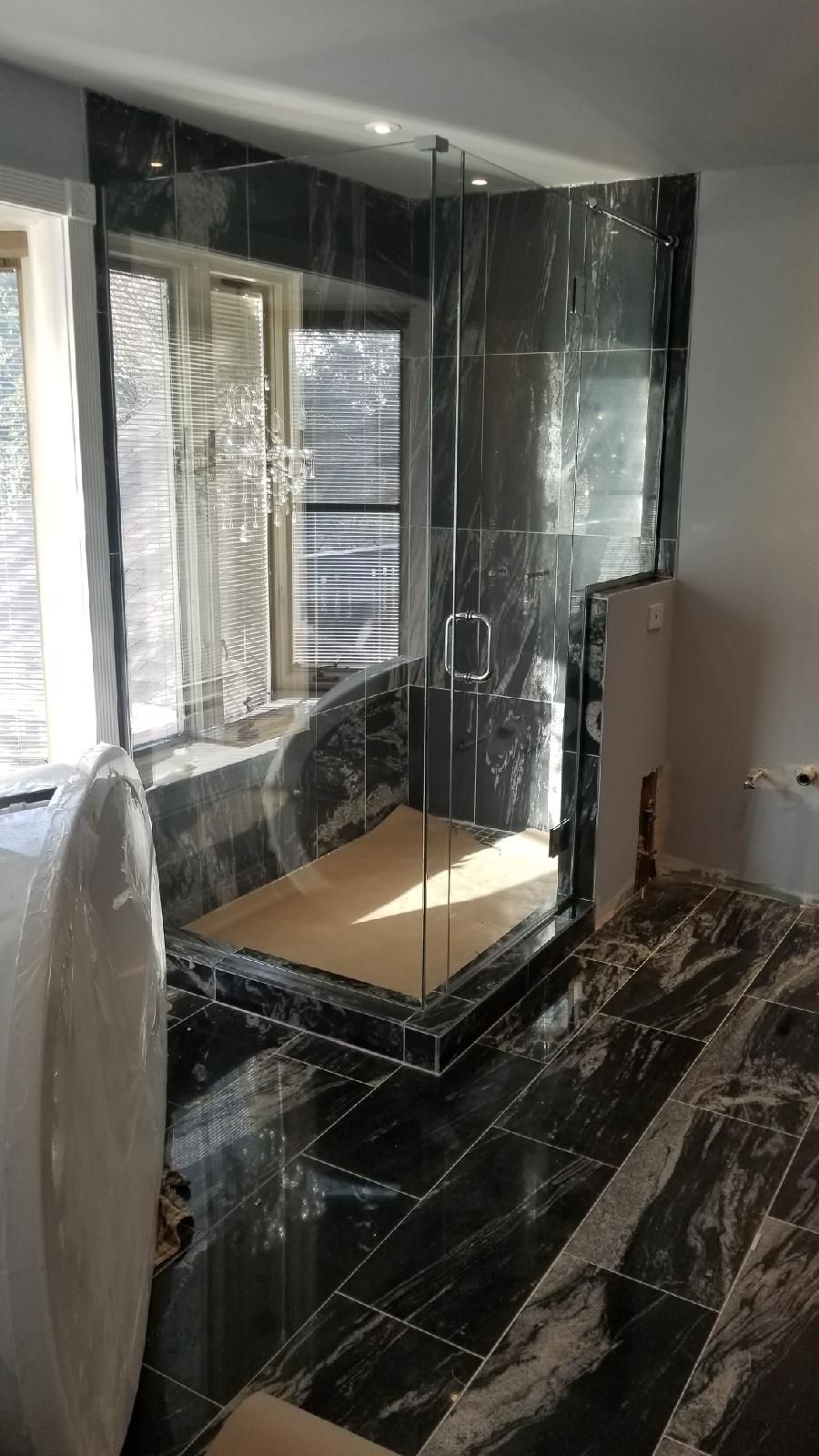 A bathroom with a walk in shower and black tiles.