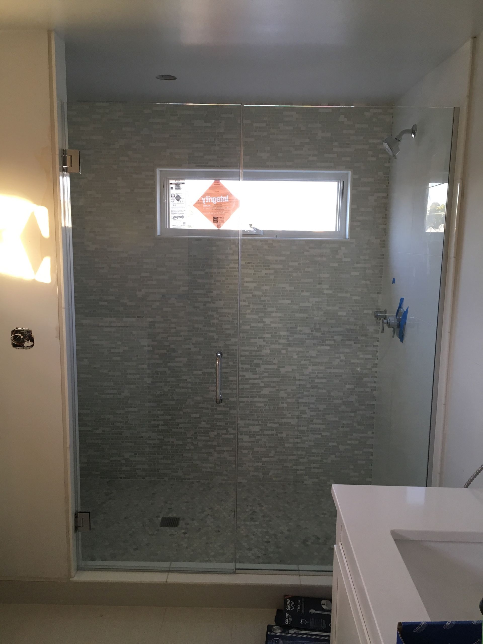 A bathroom with a glass shower door and a sink.