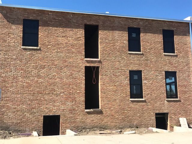 A large brick building with black windows is under construction.