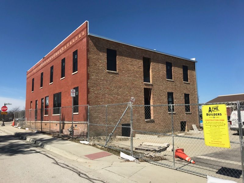A large red brick building is behind a chain link fence.