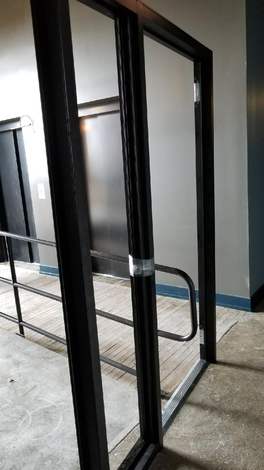 A glass door with a metal railing in a hallway.