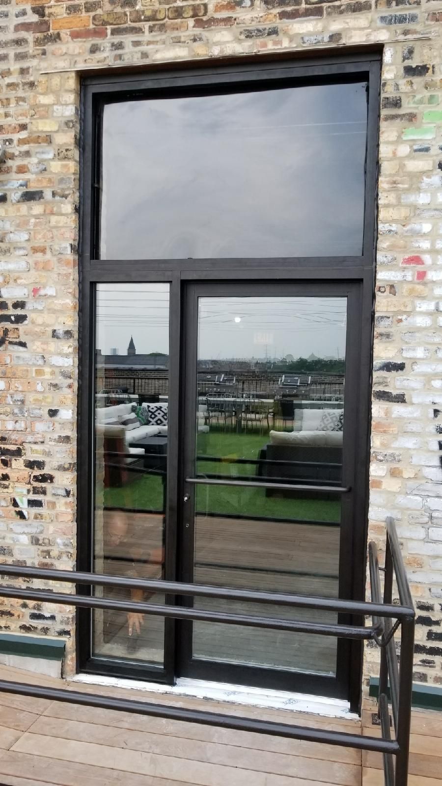 A large glass door is sitting on the side of a brick building.