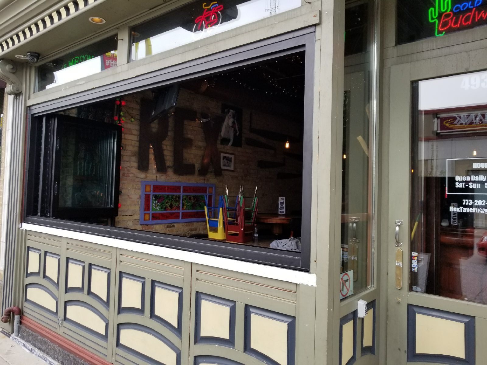 A restaurant with a large window and a neon sign that says budweiser