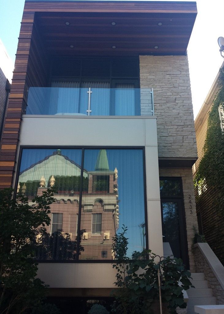 A house with a balcony and a reflection of a church in the windows