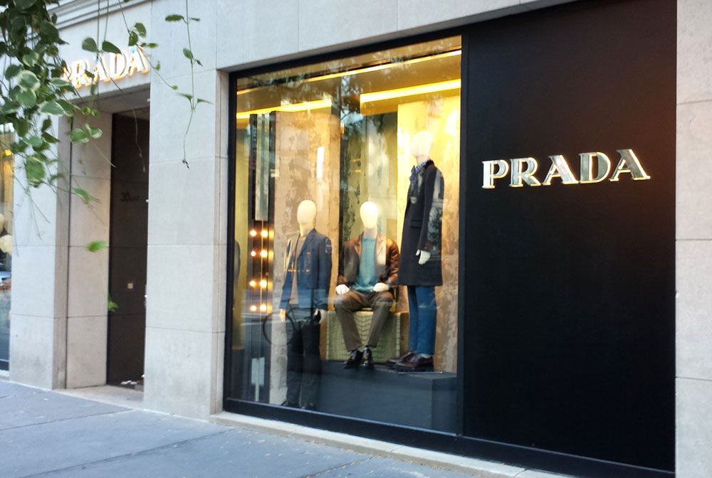 The front of a prada store with mannequins in the window.