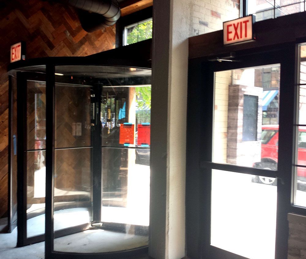 A red exit sign is above a glass door