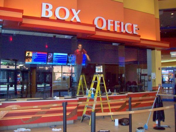 A man standing on a ladder in front of a box office