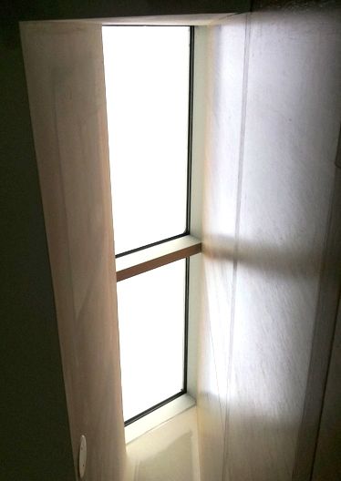 A window with a white curtain on it and a light coming through it.