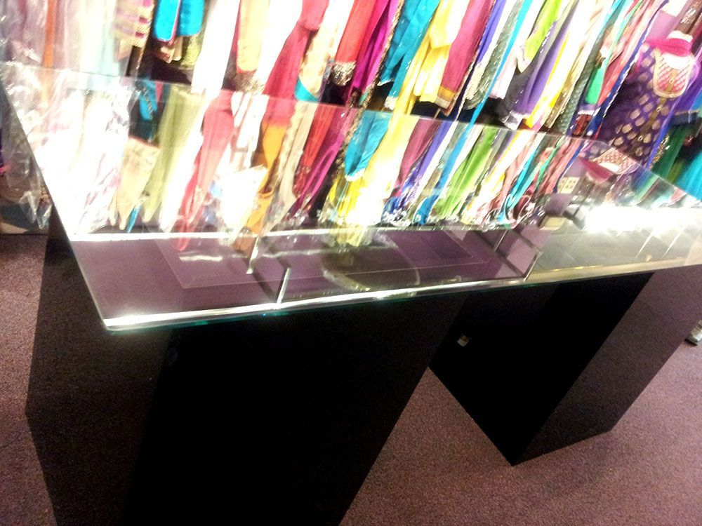 A glass table in front of a display of clothes
