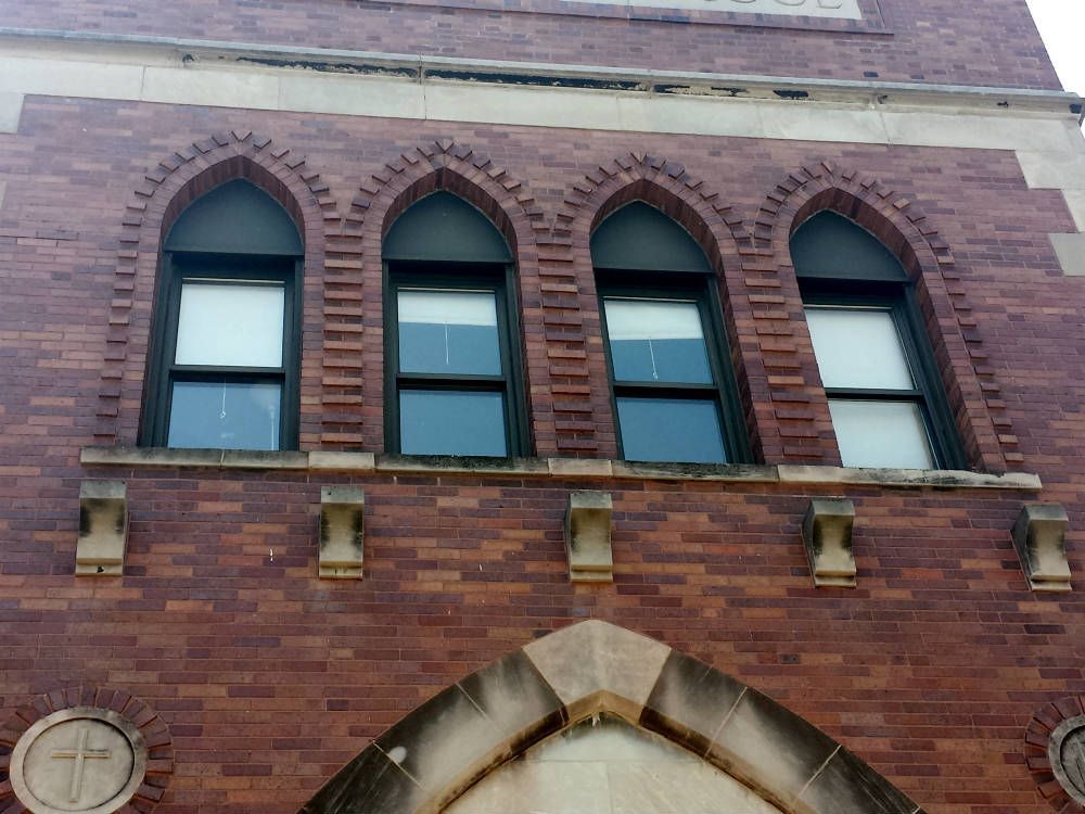 A brick building with arched windows and a cross on it