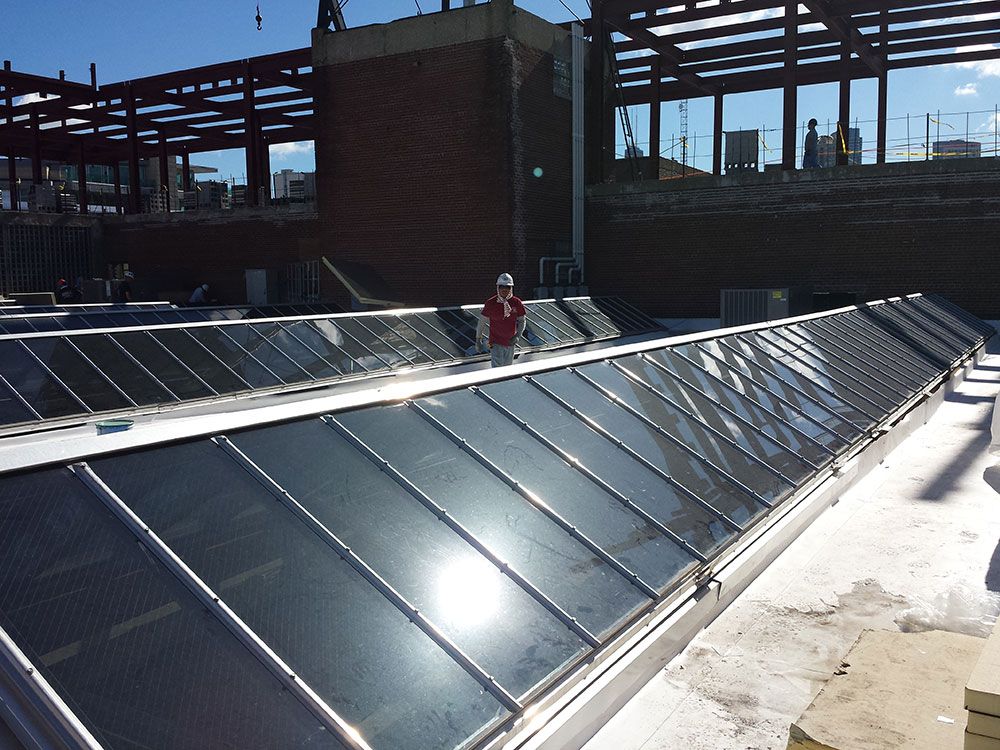 A man standing on top of a roof with a lot of windows