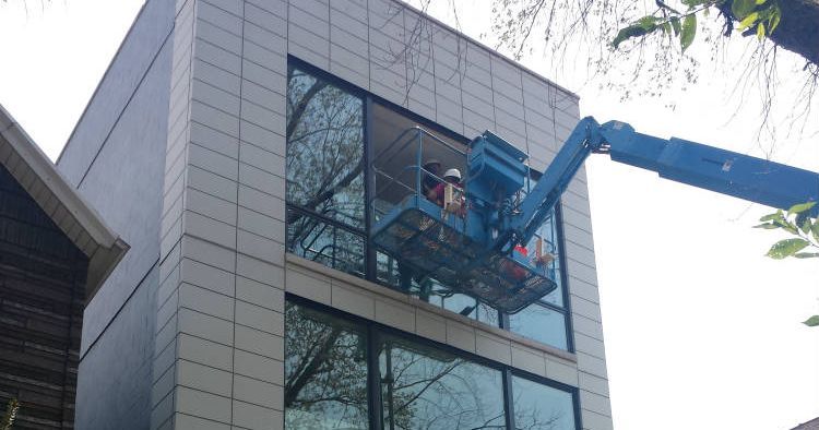 A man is cleaning the windows of a building with a crane.