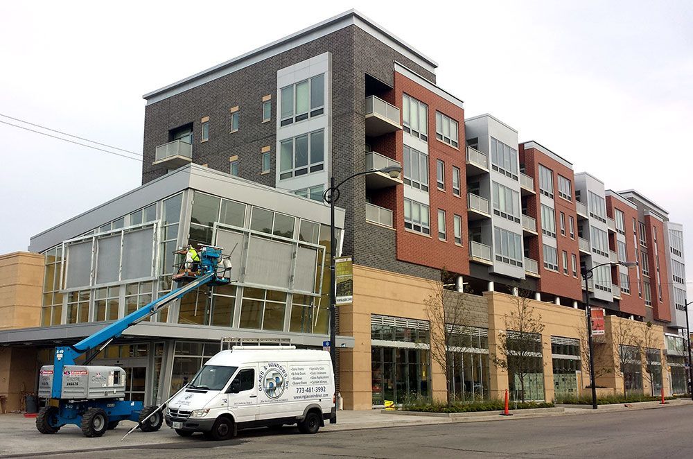 A white van is parked in front of a large building.