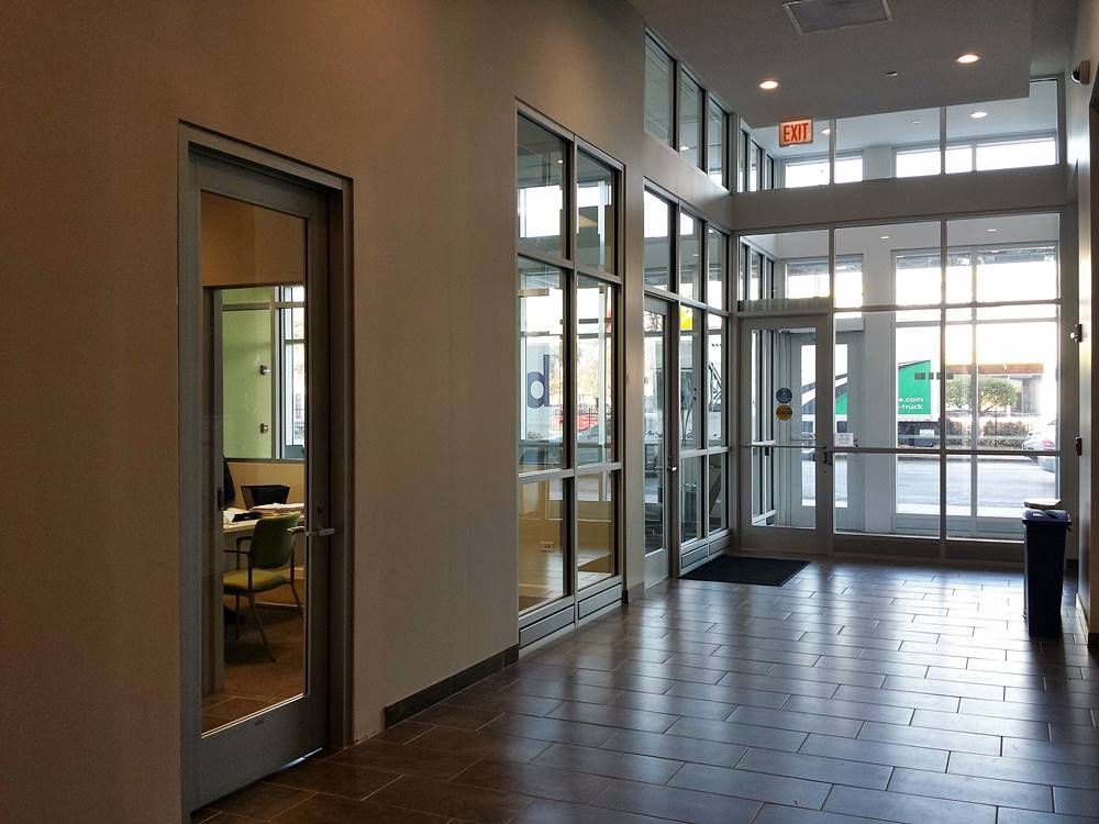 A hallway with a lot of windows and a red exit sign