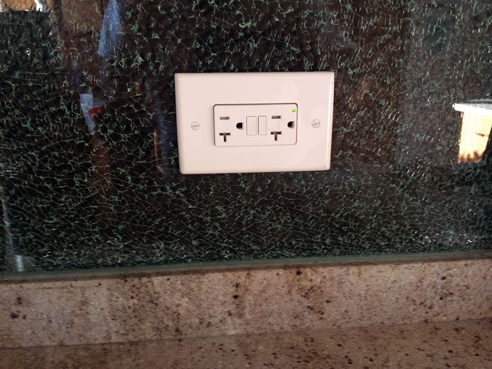 A white electrical outlet on a granite counter top