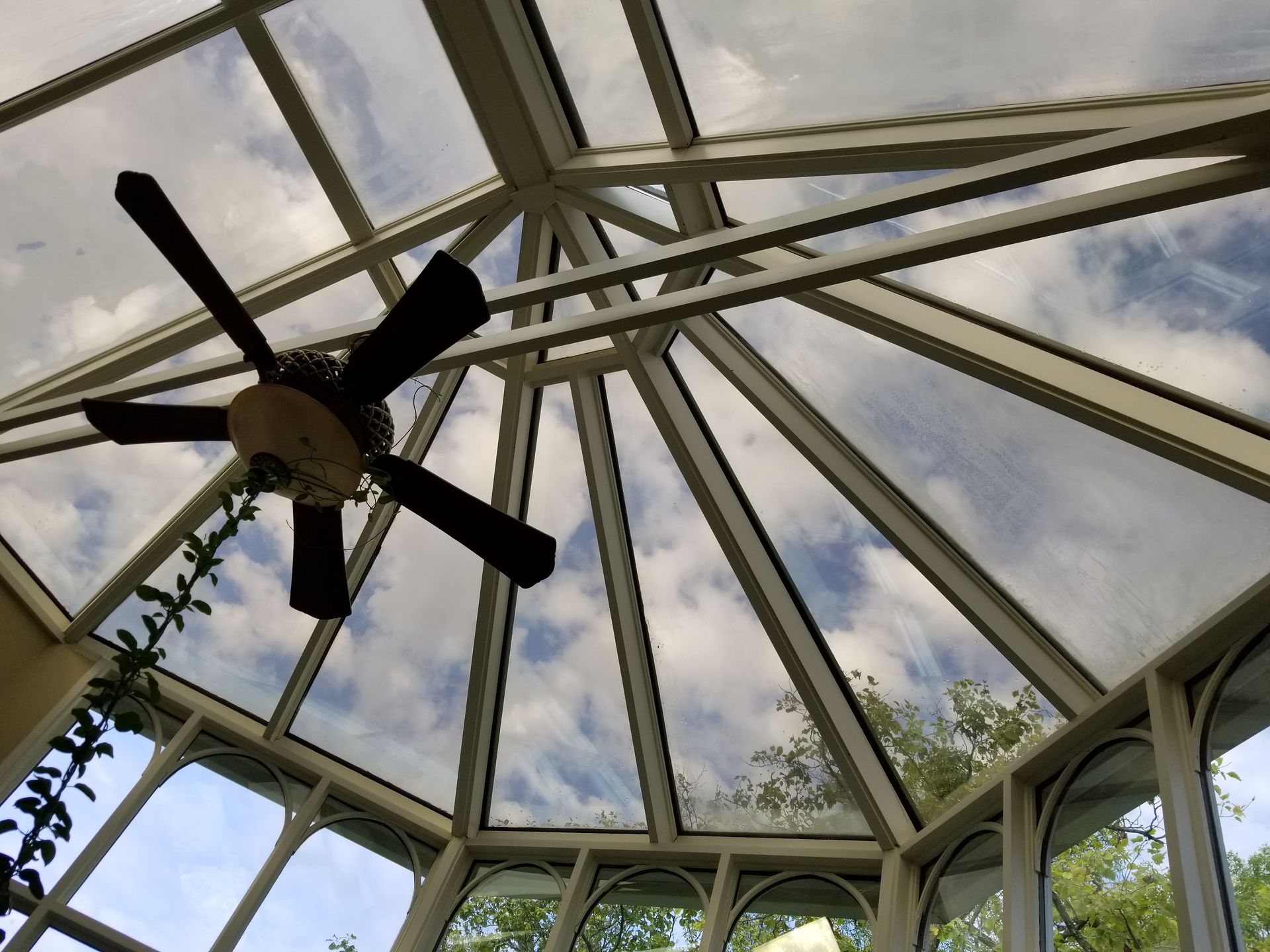 A ceiling fan is hanging from the ceiling of a conservatory