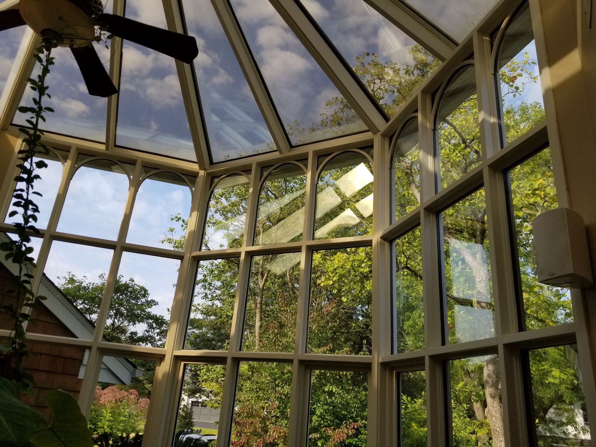 A conservatory with a ceiling fan and lots of windows