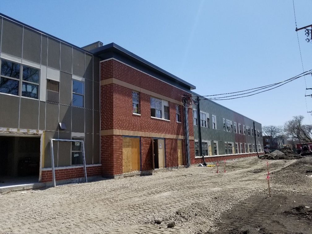 A large brick building with a lot of windows is under construction.
