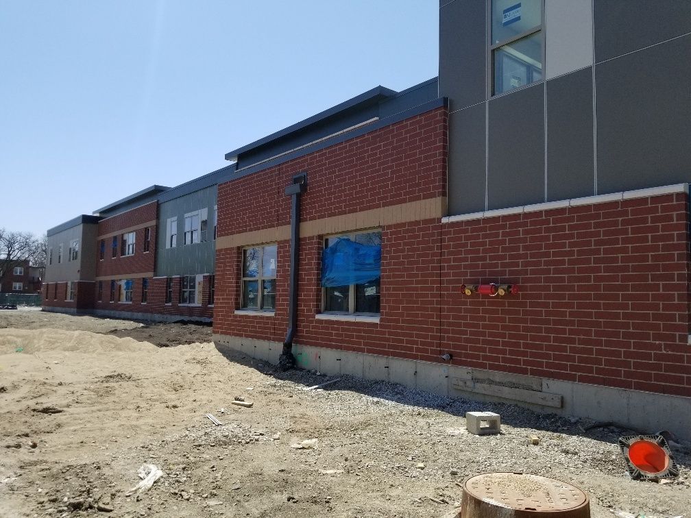 A large brick building with a lot of windows is under construction.