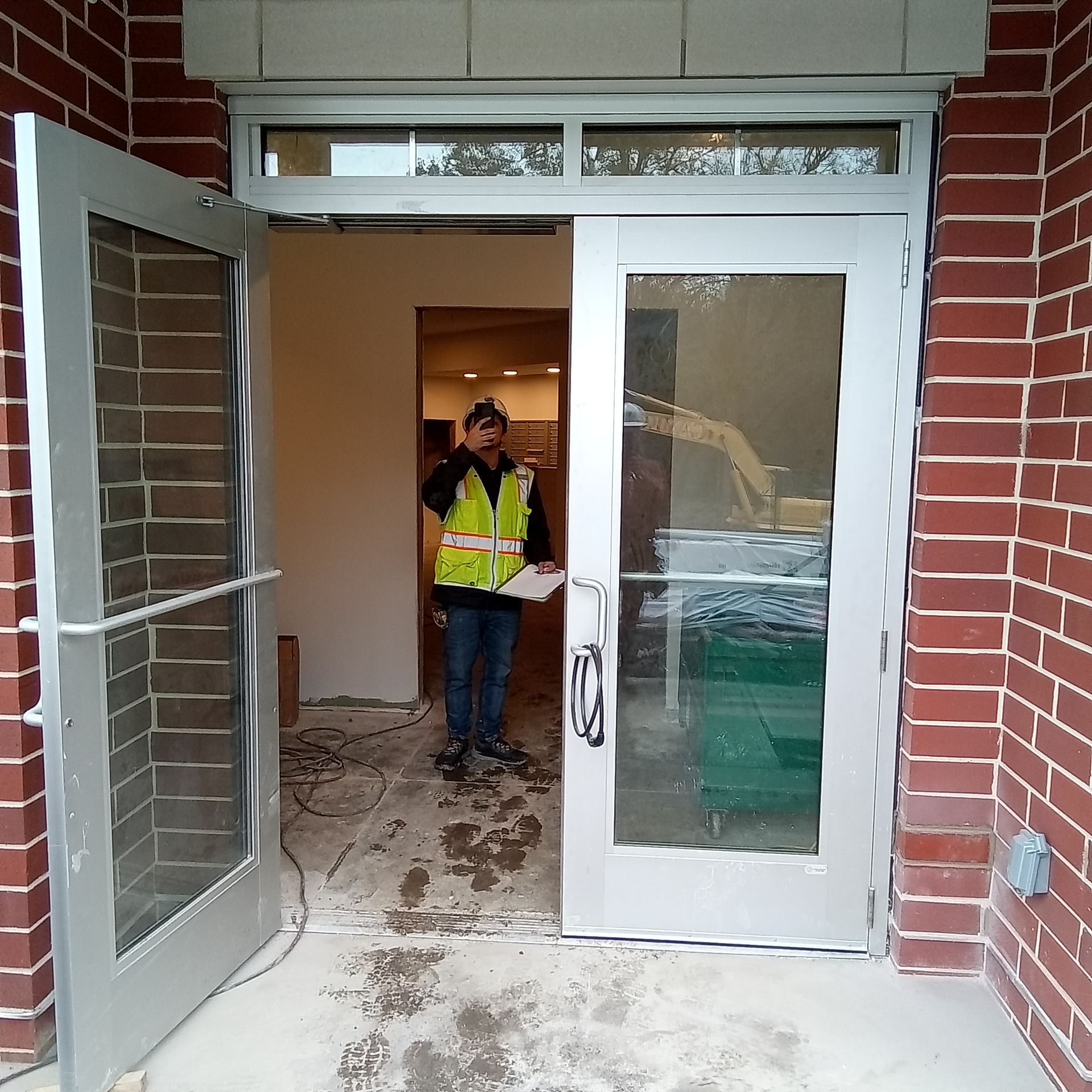 A man in a yellow vest is standing in the doorway of a building