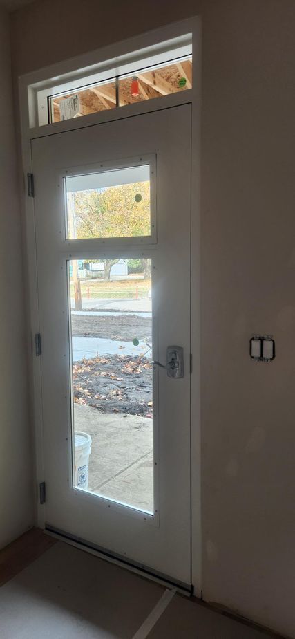 A white door with a window above it in a room.