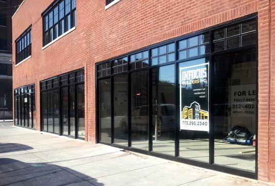 A brick building with a lot of windows and a sign in the window that says for lease